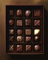 Assorted luxury chocolates in decorative box. A top view of a decorative box filled with assorted luxury chocolates, featuring intricate designs, rich colors, and a variety of flavors. photo
