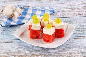 A plate with watermelon and cheese on sticks photo