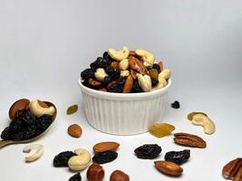 Mixed Nuts on a white bowl Almonds, Walnuts, Cashews, Hazelnuts, Dried Prunes and Raisins. Different Nut Mix. photo