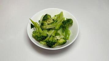 Cooked broccoli in a white bowl on a white background photo