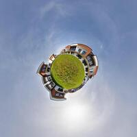 modern low-rise residential townhouse on surface of little tiny planet in blue sky with sun. Transformation of spherical panorama 360 degrees. Spherical abstract aerial view. Curvature of space. photo