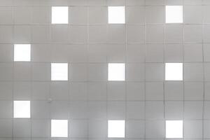cassette stretched or suspended ceiling with square halogen spots lamps and drywall construction in empty room in house or office. Looking up view photo