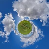 simple little tiny planet without buildings in blue sky with sun and beautiful clouds. Transformation of spherical panorama 360 degrees. Spherical abstract aerial view. Curvature of space. photo