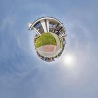 modern low-rise residential townhouse on surface of little tiny planet in blue sky with sun. Transformation of spherical panorama 360 degrees. Spherical abstract aerial view. Curvature of space. photo
