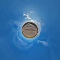 simple little tiny planet without buildings in blue sky with sun and beautiful clouds. Transformation of spherical panorama 360 degrees. Spherical abstract aerial view. Curvature of space. photo