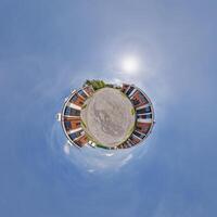 modern low-rise residential townhouse on surface of little tiny planet in blue sky with sun. Transformation of spherical panorama 360 degrees. Spherical abstract aerial view. Curvature of space. photo