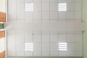 cassette stretched or suspended ceiling with square halogen spots lamps and drywall construction in empty room in house or office. Looking up view photo
