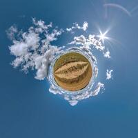 simple little tiny planet without buildings in blue sky with sun and beautiful clouds. Transformation of spherical panorama 360 degrees. Spherical abstract aerial view. Curvature of space. photo