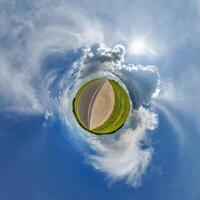 simple little tiny planet without buildings in blue sky with sun and beautiful clouds. Transformation of spherical panorama 360 degrees. Spherical abstract aerial view. Curvature of space. photo