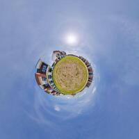 modern low-rise residential townhouse on surface of little tiny planet in blue sky with sun. Transformation of spherical panorama 360 degrees. Spherical abstract aerial view. Curvature of space. photo