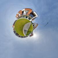 modern low-rise residential townhouse on surface of little tiny planet in blue sky with sun. Transformation of spherical panorama 360 degrees. Spherical abstract aerial view. Curvature of space. photo