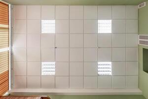 cassette stretched or suspended ceiling with square halogen spots lamps and drywall construction in empty room in house or office. Looking up view photo