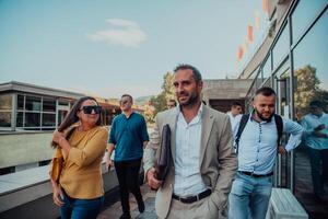 A diverse group of businessmen and colleagues walking together by their workplace, showcasing collaboration and teamwork in the company. photo
