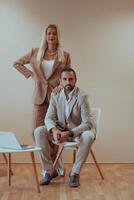 A business couple posing for a photograph together against a beige backdrop, capturing their professional partnership and creating a timeless image of unity and success. photo