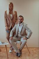 A business couple posing for a photograph together against a beige backdrop, capturing their professional partnership and creating a timeless image of unity and success. photo