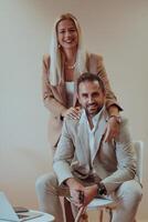 A business couple posing for a photograph together against a beige backdrop, capturing their professional partnership and creating a timeless image of unity and success. photo