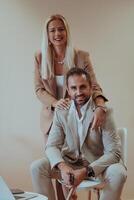 A business couple posing for a photograph together against a beige backdrop, capturing their professional partnership and creating a timeless image of unity and success. photo
