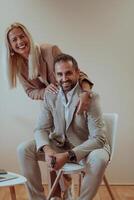 A business couple posing for a photograph together against a beige backdrop, capturing their professional partnership and creating a timeless image of unity and success. photo