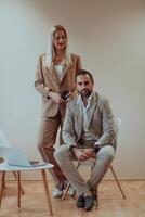 A business couple posing for a photograph together against a beige backdrop, capturing their professional partnership and creating a timeless image of unity and success. photo