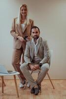 A business couple posing for a photograph together against a beige backdrop, capturing their professional partnership and creating a timeless image of unity and success. photo