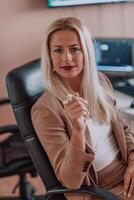 A businesswoman sitting in a programmer's office surrounded by computers, showing her expertise and dedication to technology. photo