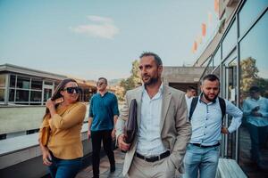 A diverse group of businessmen and colleagues walking together by their workplace, showcasing collaboration and teamwork in the company. photo
