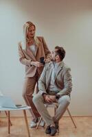 A business couple posing for a photograph together against a beige backdrop, capturing their professional partnership and creating a timeless image of unity and success. photo