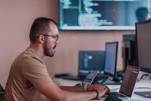 A programmer diligently testing smartphone applications while sitting in their office. photo