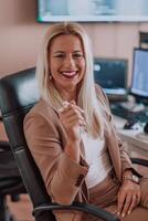 A businesswoman sitting in a programmer's office surrounded by computers, showing her expertise and dedication to technology. photo