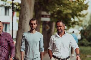 After a productive day at work, a group of diverse colleagues enjoy a leisurely stroll through a modern and natural urban setting photo