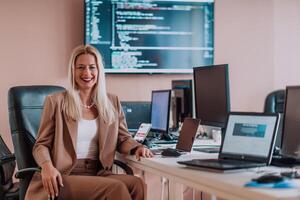 A businesswoman sitting in a programmer's office surrounded by computers, showing her expertise and dedication to technology. photo