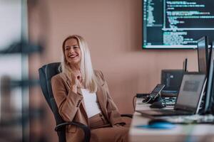 A businesswoman sitting in a programmer's office surrounded by computers, showing her expertise and dedication to technology. photo