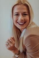 A confident and successful businesswoman, with a wide smile, strikes a pose in front of a beige background, exuding professionalism and elegance photo
