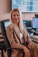 A businesswoman sitting in a programmer's office surrounded by computers, showing her expertise and dedication to technology. photo