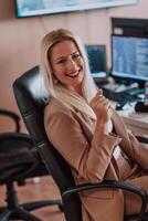 A businesswoman sitting in a programmer's office surrounded by computers, showing her expertise and dedication to technology. photo