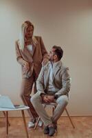 A business couple posing for a photograph together against a beige backdrop, capturing their professional partnership and creating a timeless image of unity and success. photo