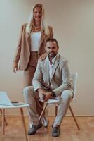 A business couple posing for a photograph together against a beige backdrop, capturing their professional partnership and creating a timeless image of unity and success. photo
