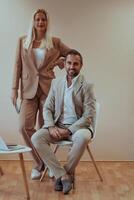 A business couple posing for a photograph together against a beige backdrop, capturing their professional partnership and creating a timeless image of unity and success. photo