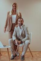 A business couple posing for a photograph together against a beige backdrop, capturing their professional partnership and creating a timeless image of unity and success. photo