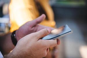 Closeup photo of businessman hand utilizes his smartphone outdoors, showcasing the seamless integration of technology and mobility in modern professional life.