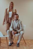 A business couple posing for a photograph together against a beige backdrop, capturing their professional partnership and creating a timeless image of unity and success. photo