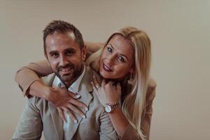 A business couple posing for a photograph together against a beige backdrop, capturing their professional partnership and creating a timeless image of unity and success. photo