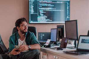 A programmer diligently testing smartphone applications while sitting in their office. photo
