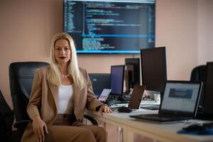 A businesswoman sitting in a programmer's office surrounded by computers photo