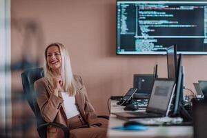 A businesswoman sitting in a programmer's office surrounded by computers, showing her expertise and dedication to technology. photo