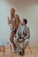 A business couple posing for a photograph together against a beige backdrop, capturing their professional partnership and creating a timeless image of unity and success. photo
