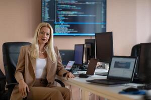 A businesswoman sitting in a programmer's office surrounded by computers photo