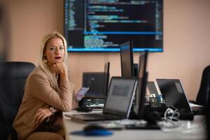 A businesswoman sitting in a programmer's office surrounded by computers photo