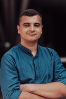 A successful young businessman in a shirt, with crossed arms, poses outdoors, confident expression on his face. photo