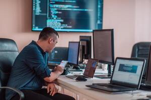A programmer diligently testing smartphone applications while sitting in their office. photo